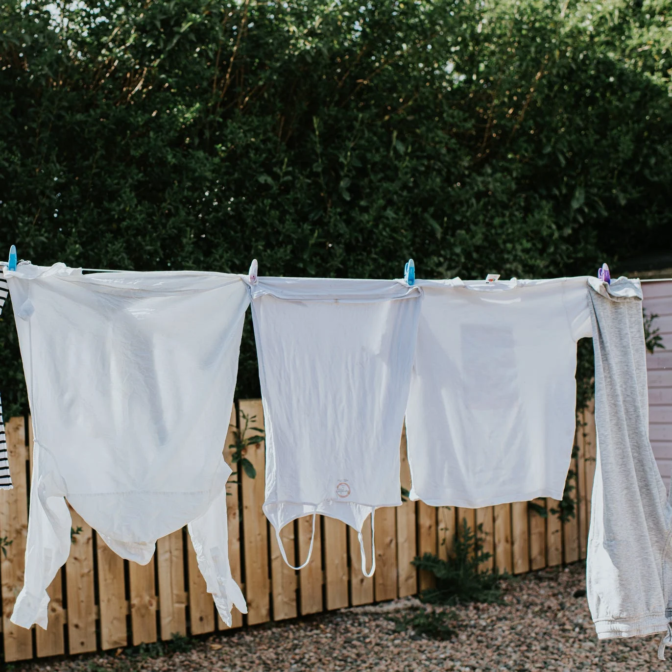 A row of white washing hangs on a washing line, drying in the sun.