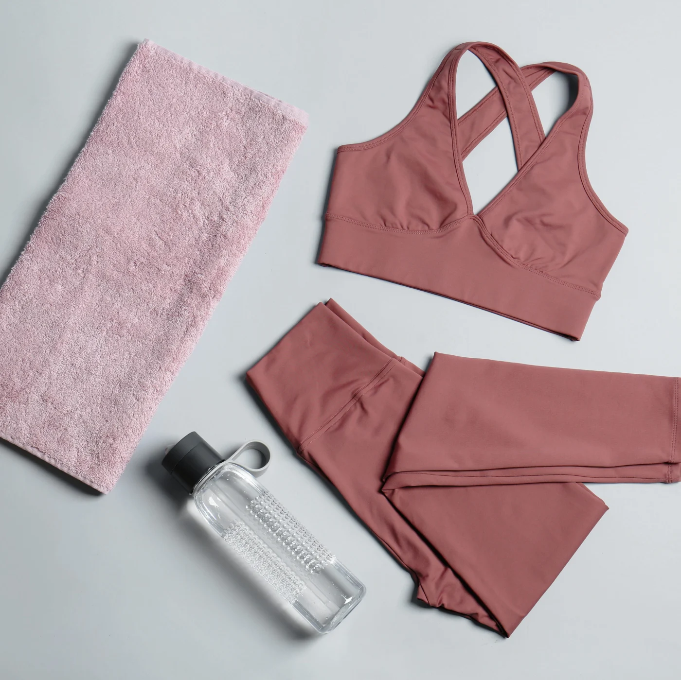 Sportswear, bottle of water and towel on grey background, flat lay. Yoga equipment